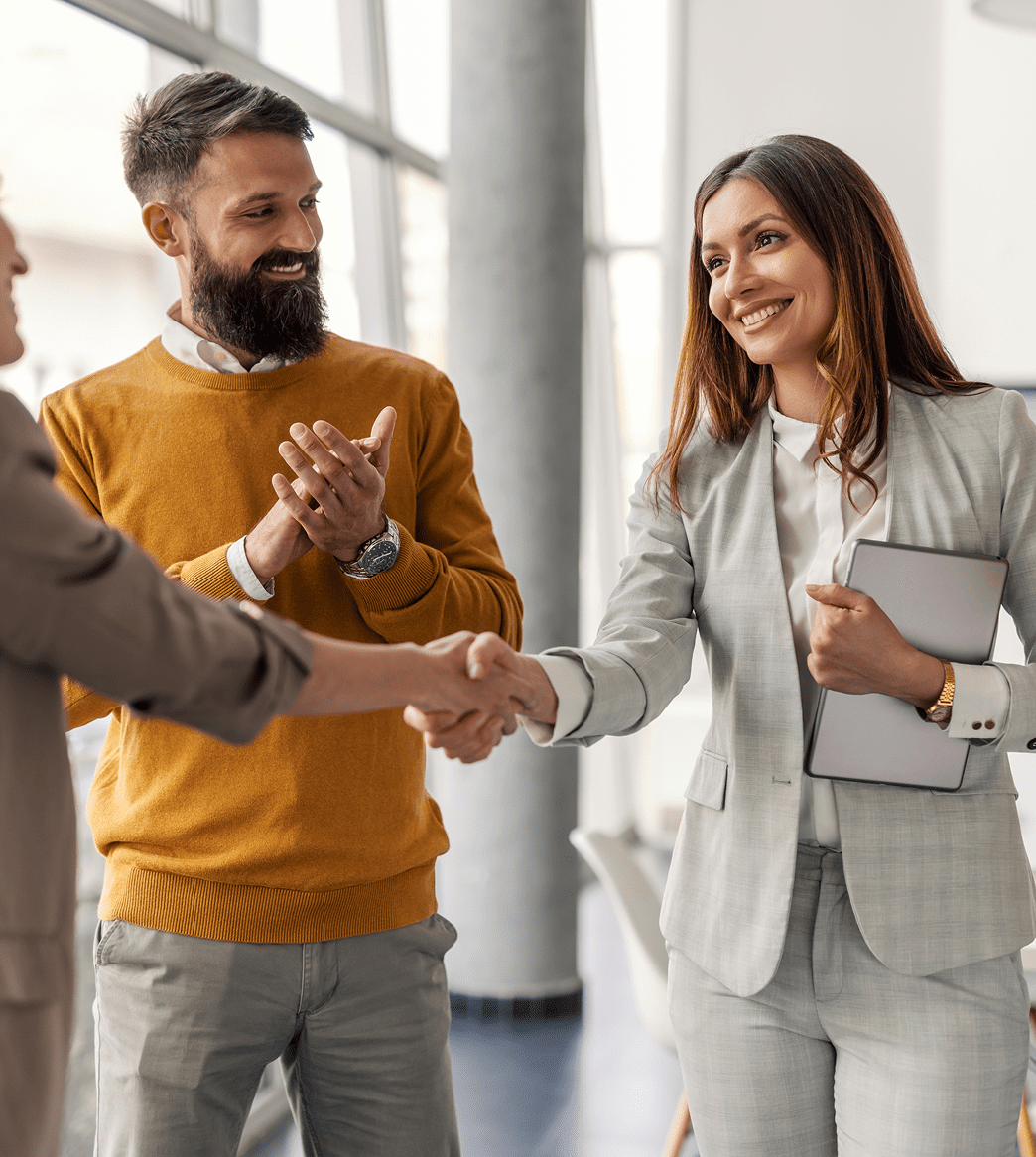Business professionals shaking hands and smiling.