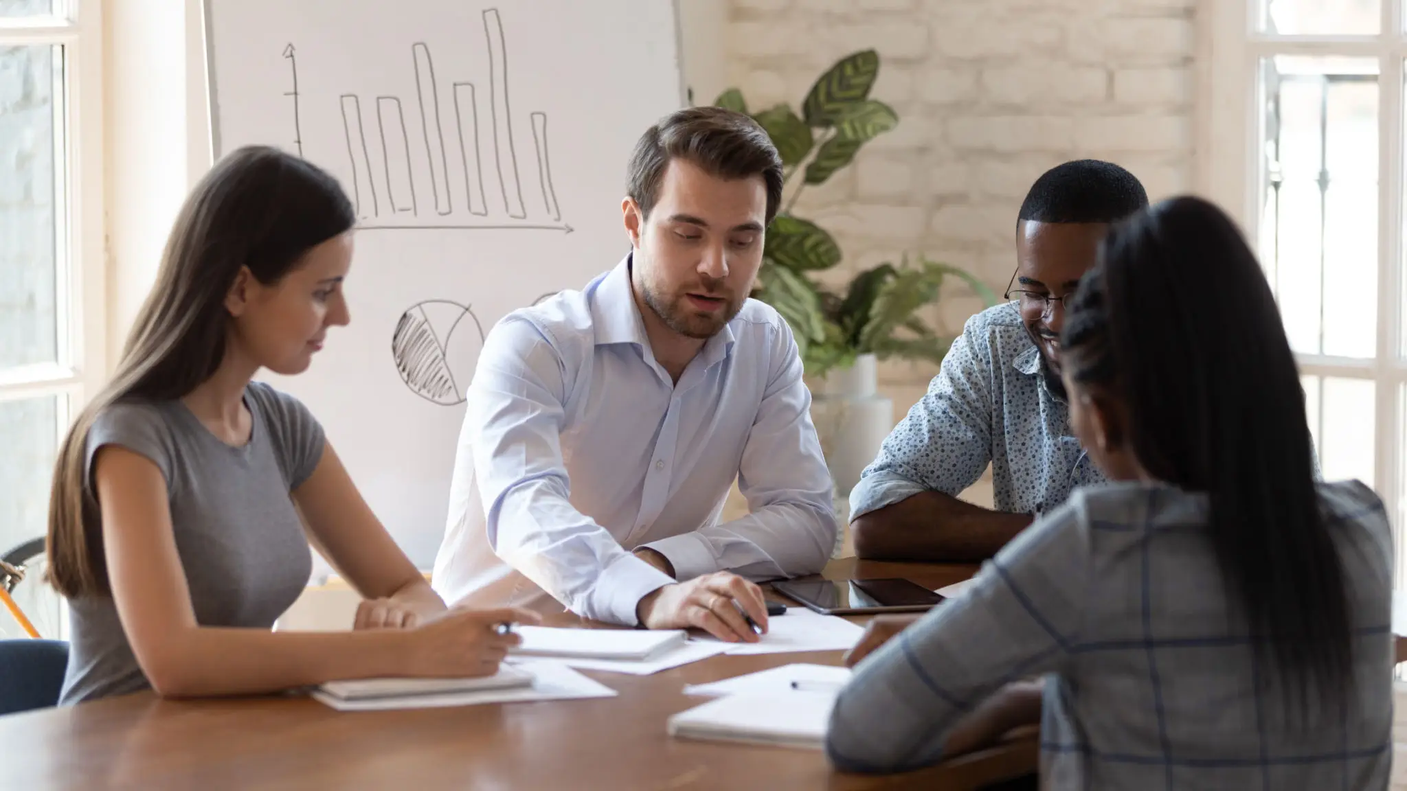 A diverse group of four colleagues sits around a table in discussion