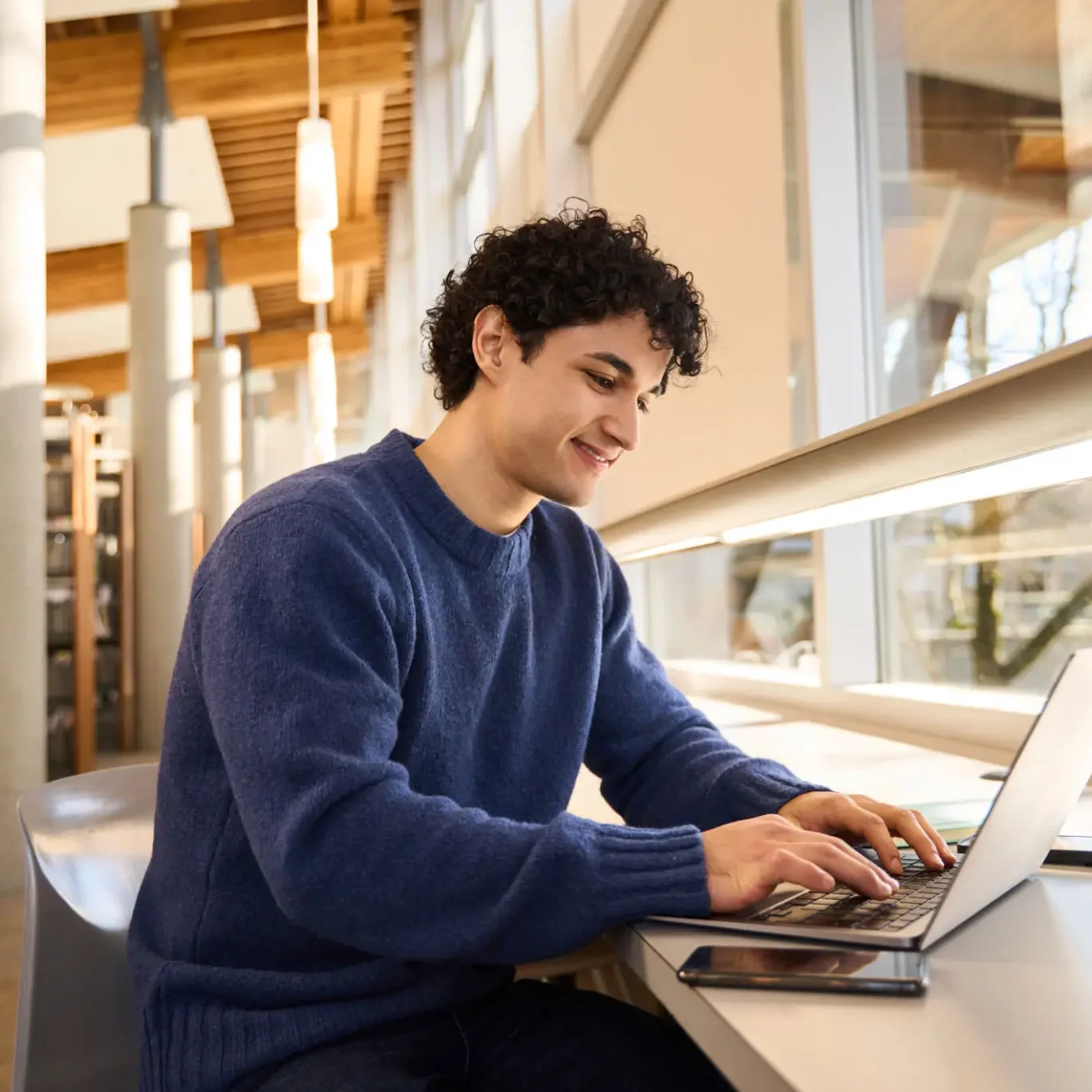 A student operating a laptop in a library