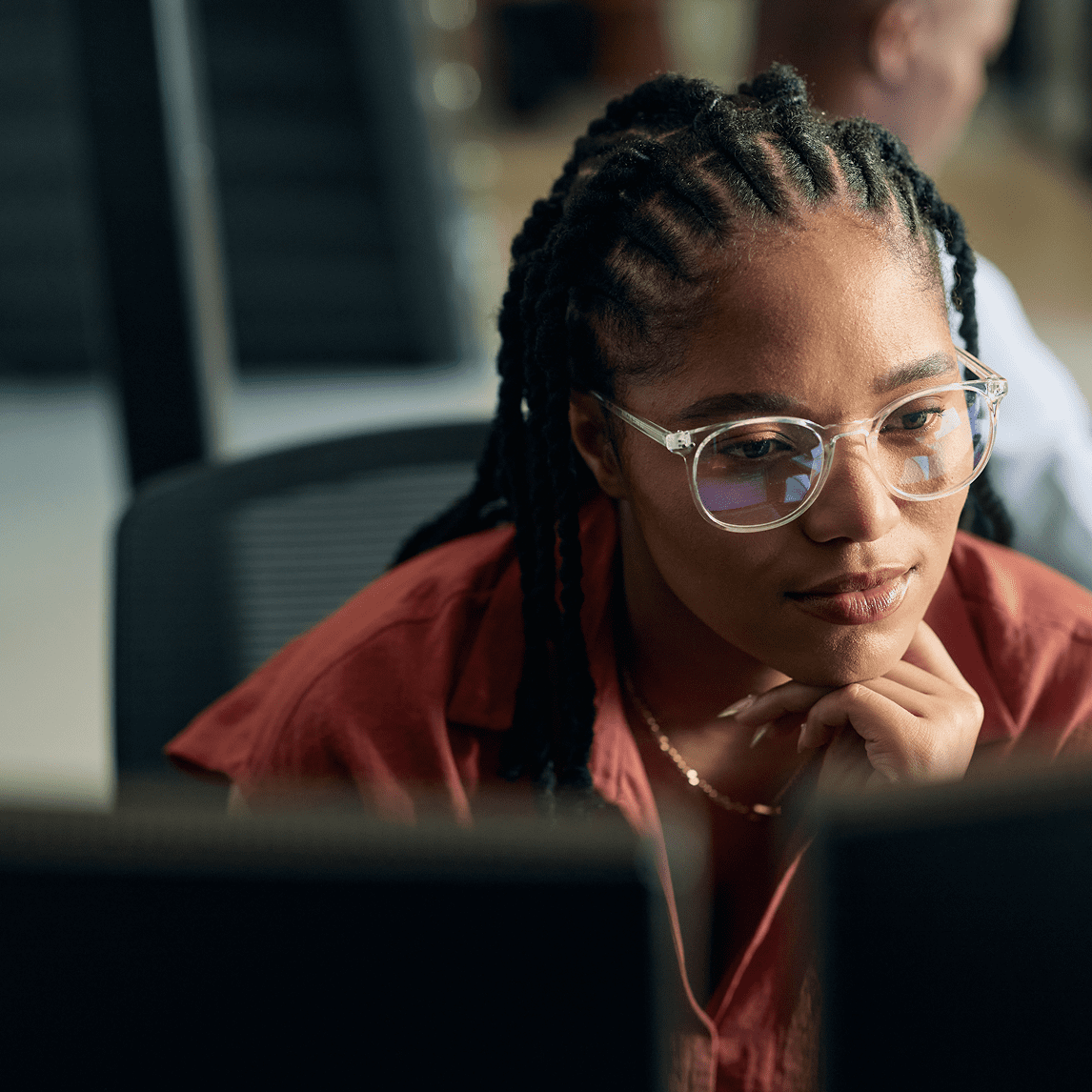 Woman focused on computer screen, wearing glasses.